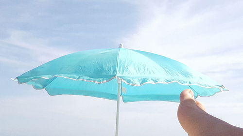 Person holding umbrella against sky