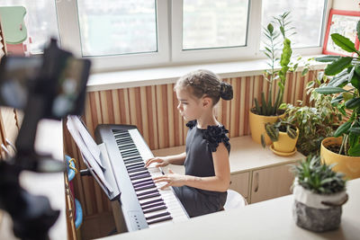 Side view of girl playing piano at home