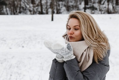 Portrait of young woman standing on snow covered field