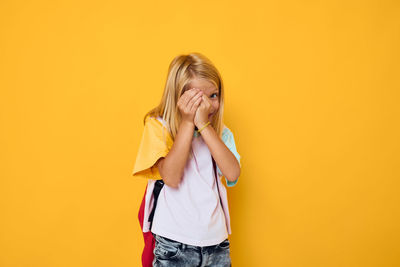 Young woman standing against yellow background