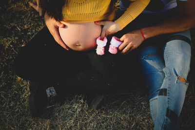 High angle view of pregnant woman with man holding baby booties