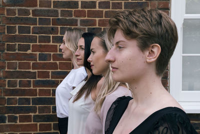 Non-binary person with friends standing side by side in front of wall