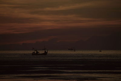Silhouette man sailing on sea against sky during sunset