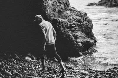 Side view of man walking down rocky huntington beach