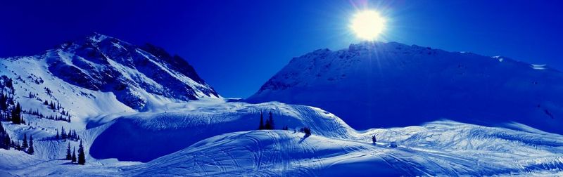 Low angle view of snow covered mountain against blue sky