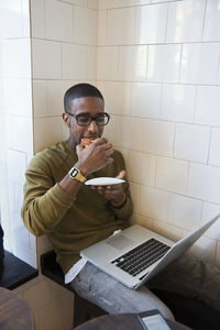 Young man in cafe eating bun, stockholm, sweden