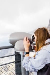 Young women looks at mountain views in binoculars from observation