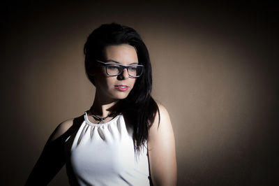 Young woman standing against brown background