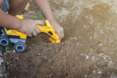 Close-up of hand holding yellow toy on beach