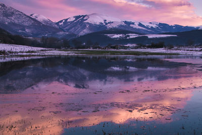 Scenic view of lake by mountains against sky during sunset