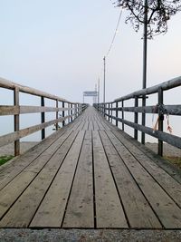 Empty wooden footbridge against sky