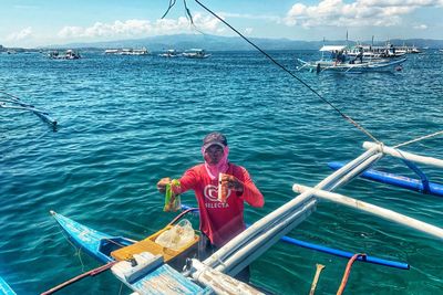 Man sitting on boat in sea against sky