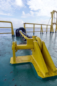 Yellow railing on pier by sea against sky