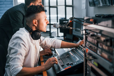 Conception of teamwork. two guys is indoors in the radio studio is busy by broadcast.