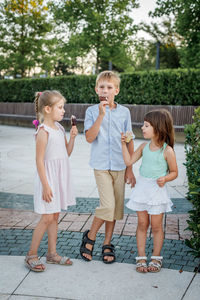 Full length of siblings standing against wall