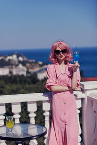 Young woman wearing sunglasses while standing against sky