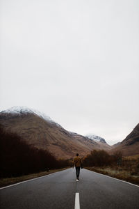 Rear view of man on road against sky