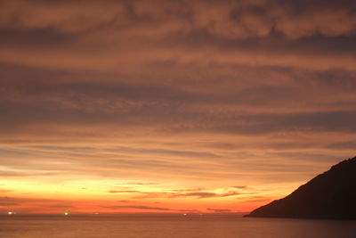 Scenic view of sea against dramatic sky during sunset