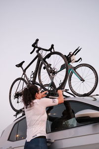 Full length of woman with bicycle standing against clear sky