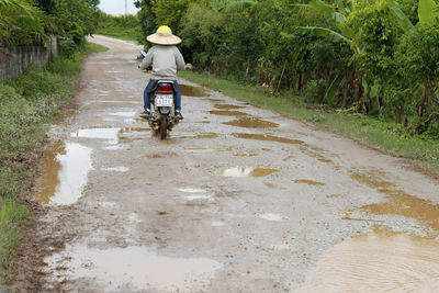 Man riding motorcycle on road in rainy season