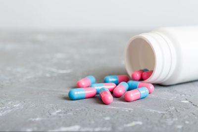 Close-up of pills spilling from bottle on table