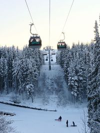 Ski lift over snow covered land against sky