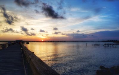 Pier over sea against sky during sunset