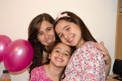 Portrait of smiling woman with daughters at home