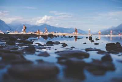 Stones in sea with people in background