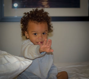 Portrait of smiling cute baby girl sitting on bed at home