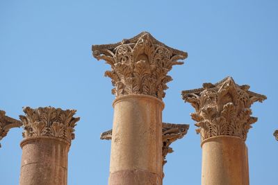 Low angle view of ancient columns against clear blue sky