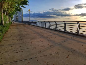 Footpath by sea against sky during sunset