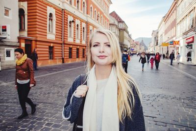 Portrait of young woman standing on street in city