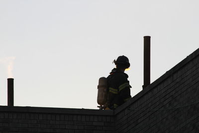 Low angle view of firefighter against clear sky