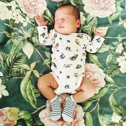 High angle view of cute baby girl sitting on bed at home