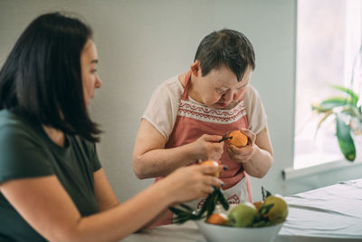 Elderly woman with down syndrome finds joy and independence in peeling mandarin with a teacher