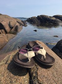 High angle view of shoes on rocks by sea against sky