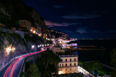 High angle view of light trails on road amidst buildings at night, amalfi, italy