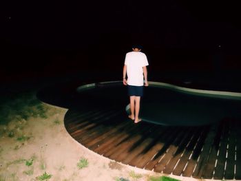 Rear view of man standing on pier at poolside