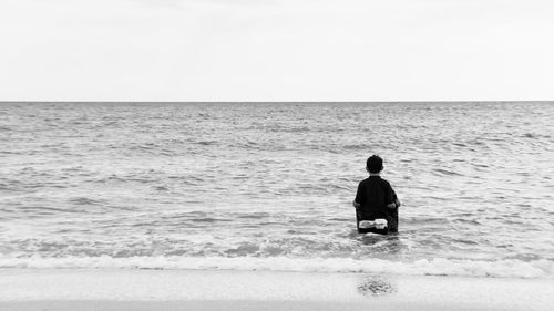 Rear view of man on beach against clear sky