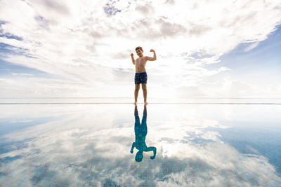 Little kid on a pools edge with a cloudly sky background