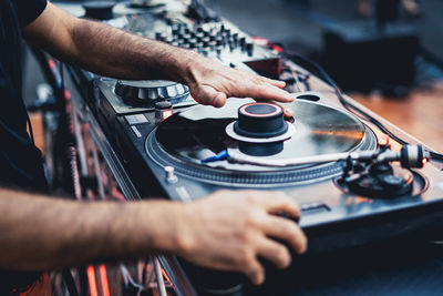 Midsection of man using turntable and sound mixer