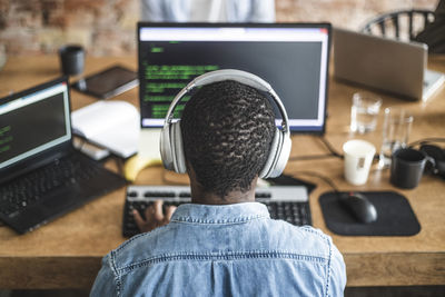 Rear view of male programmer working on computer at startup company