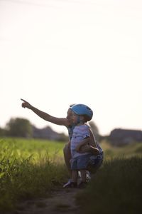 Rear view of boy playing with arms raised standing on grassy field