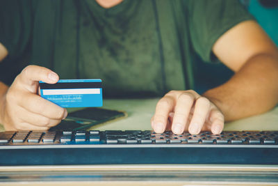 Close up a hands man holding credit card and use keyboard computer.