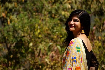 Smiling young woman looking away while standing on land