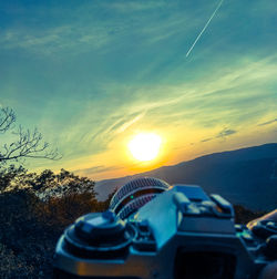 Close-up of camera against sky during sunset