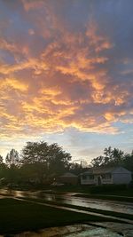 House by trees against sky during sunset