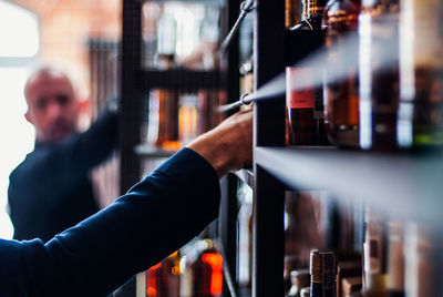 Men picking alcohol from shelf in store