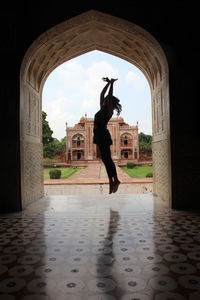 Full length of woman jumping in historic building